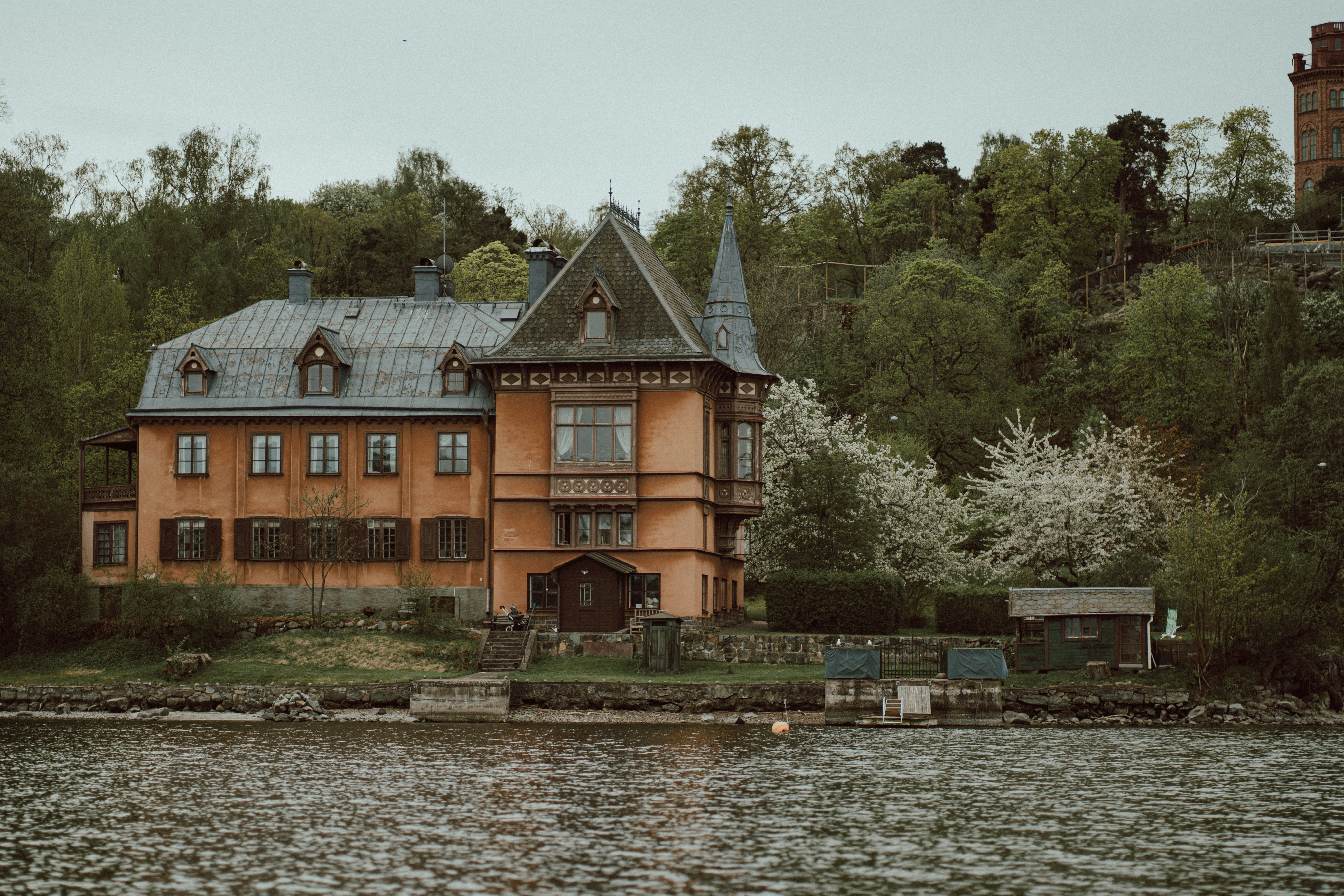 a large house sitting on top of a lake next to a forest