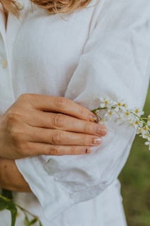 Hands gently holding a beige flower, showcasing delicate and clean nail designs