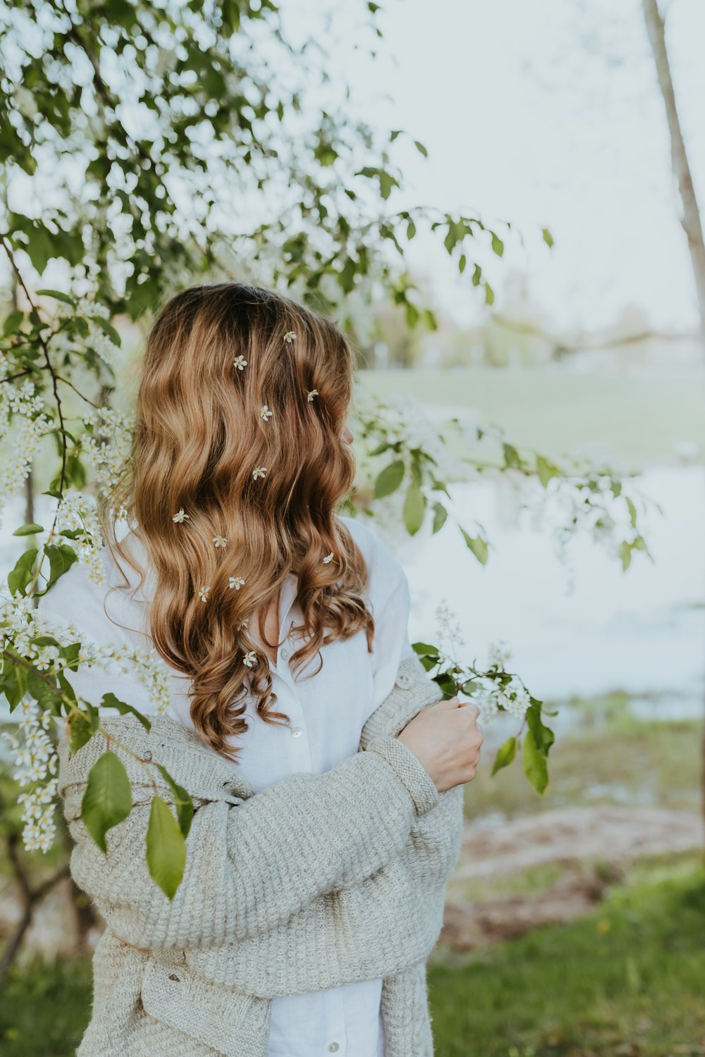 a woman standing under a tree with her arms crossed