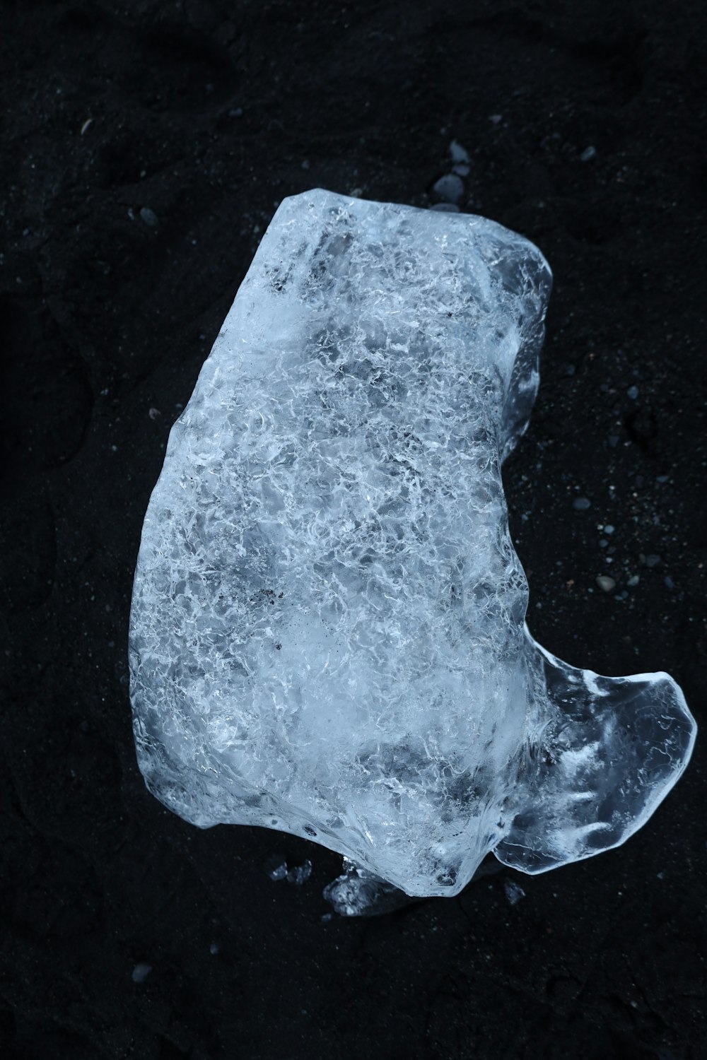 a piece of ice sitting on top of a black ground
