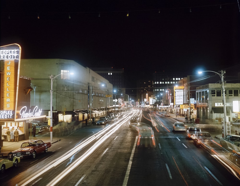 a busy city street at night with a neon sign