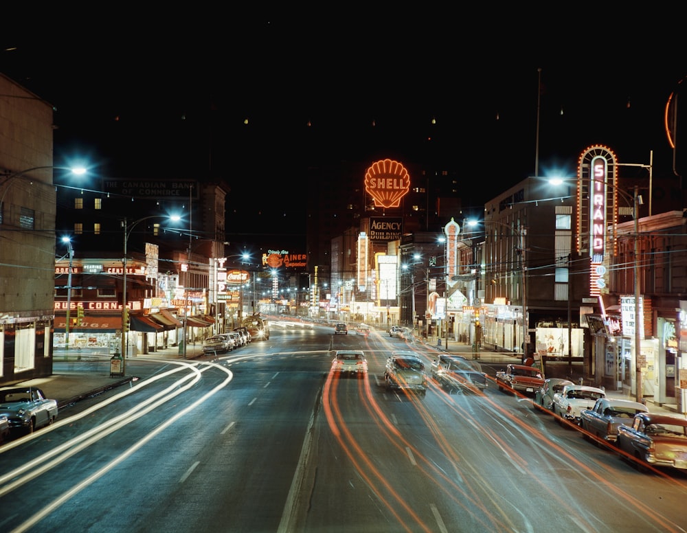 a city street at night with cars driving down it