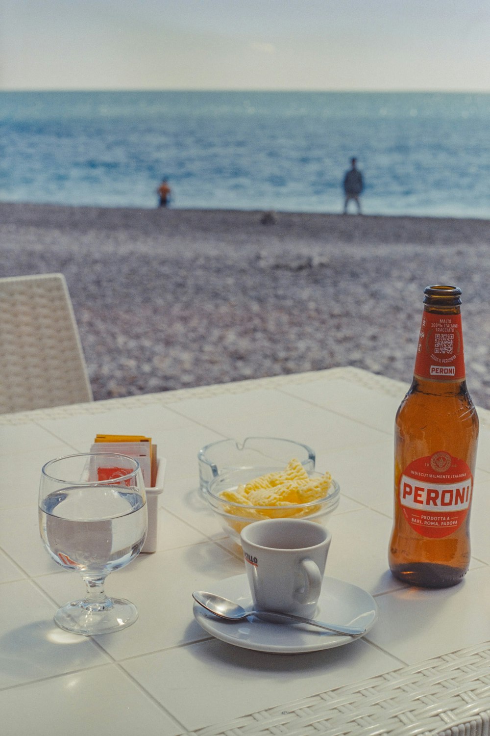 Una botella de cerveza sentada encima de una mesa junto a un tazón de comida