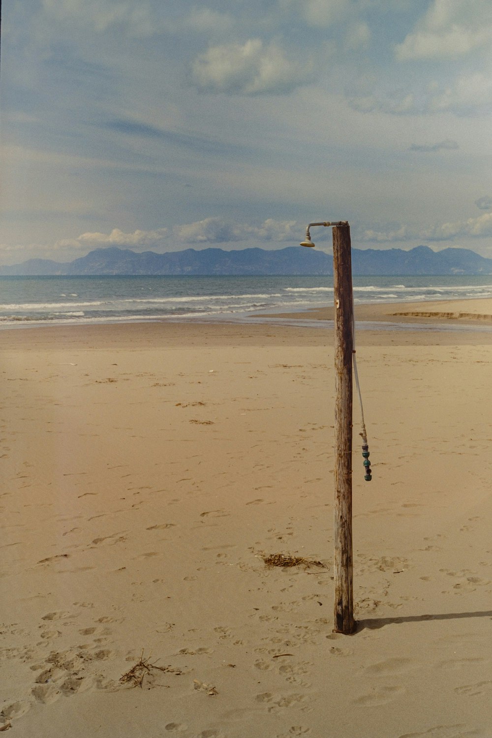 a wooden pole sticking out of the sand on a beach