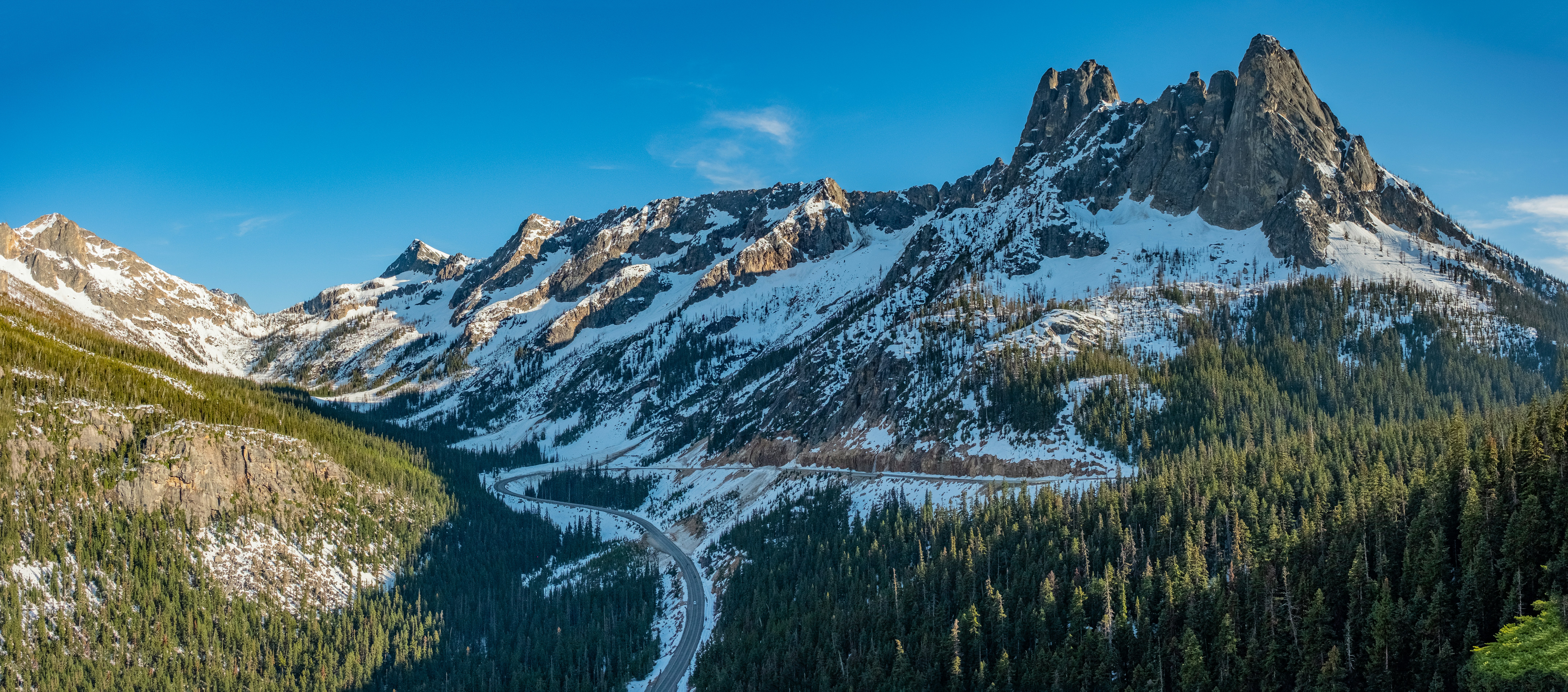 a snow covered mountain with a winding road in the foreground, Washington Pass, SR20, North Cascade National Park, WA, USA