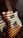 A close-up of an electric guitar with a sunburst finish. The guitar features a classic single cutaway shape with visible pickups and control knobs. Sunlight creates striped shadows across the guitar body, enhancing its wooden texture.