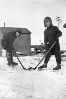 Children playing hockey on the rink, wearing colorful jerseys and smiling.