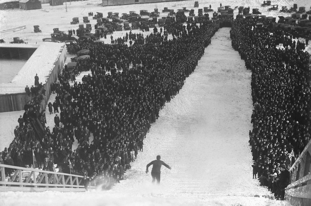 a large crowd of people standing around a man on a snowboard