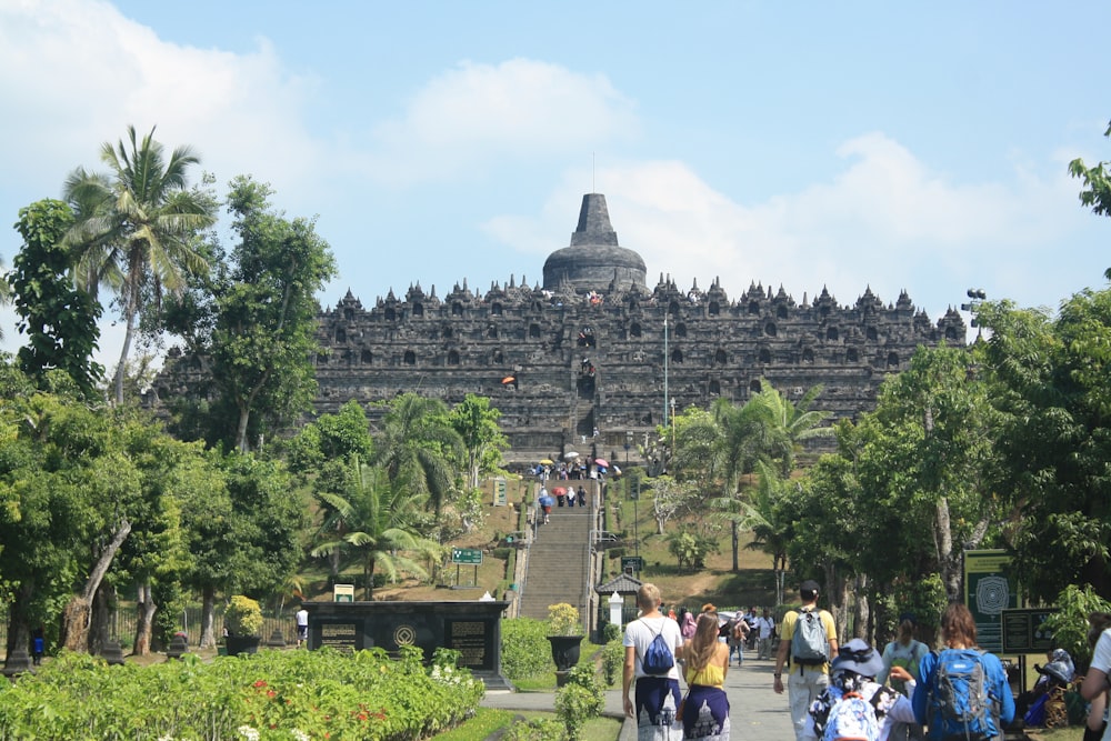 a group of people walking down a path next to a large building