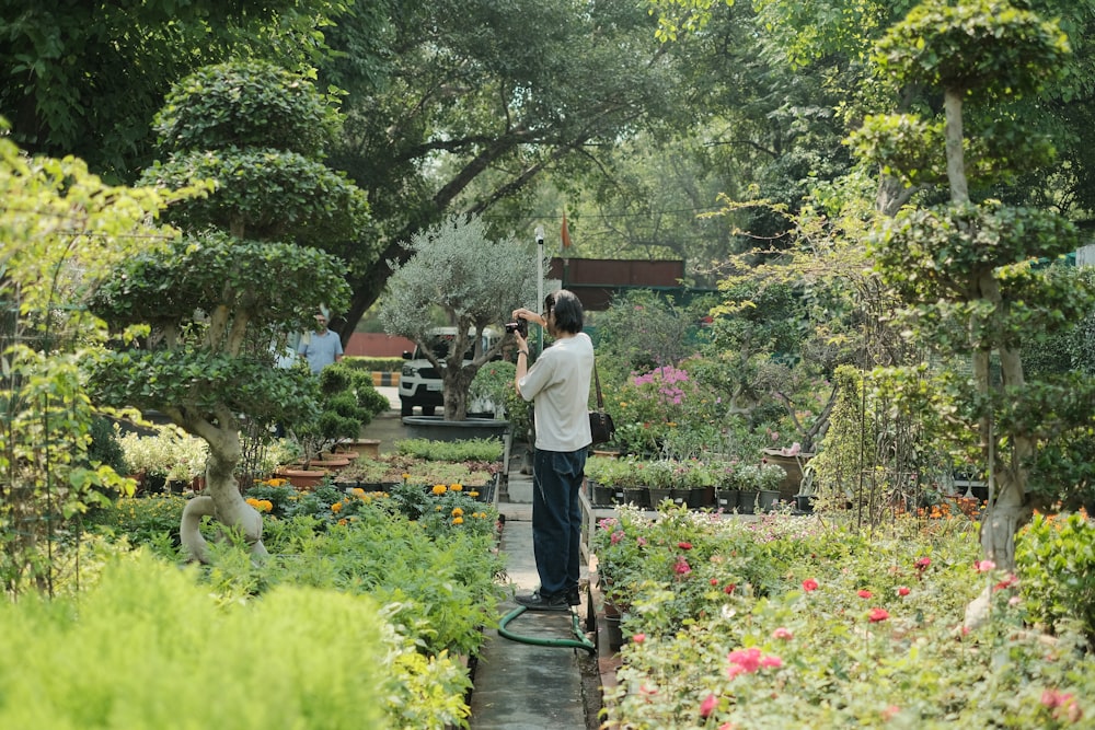 um homem em pé em um jardim segurando uma câmera