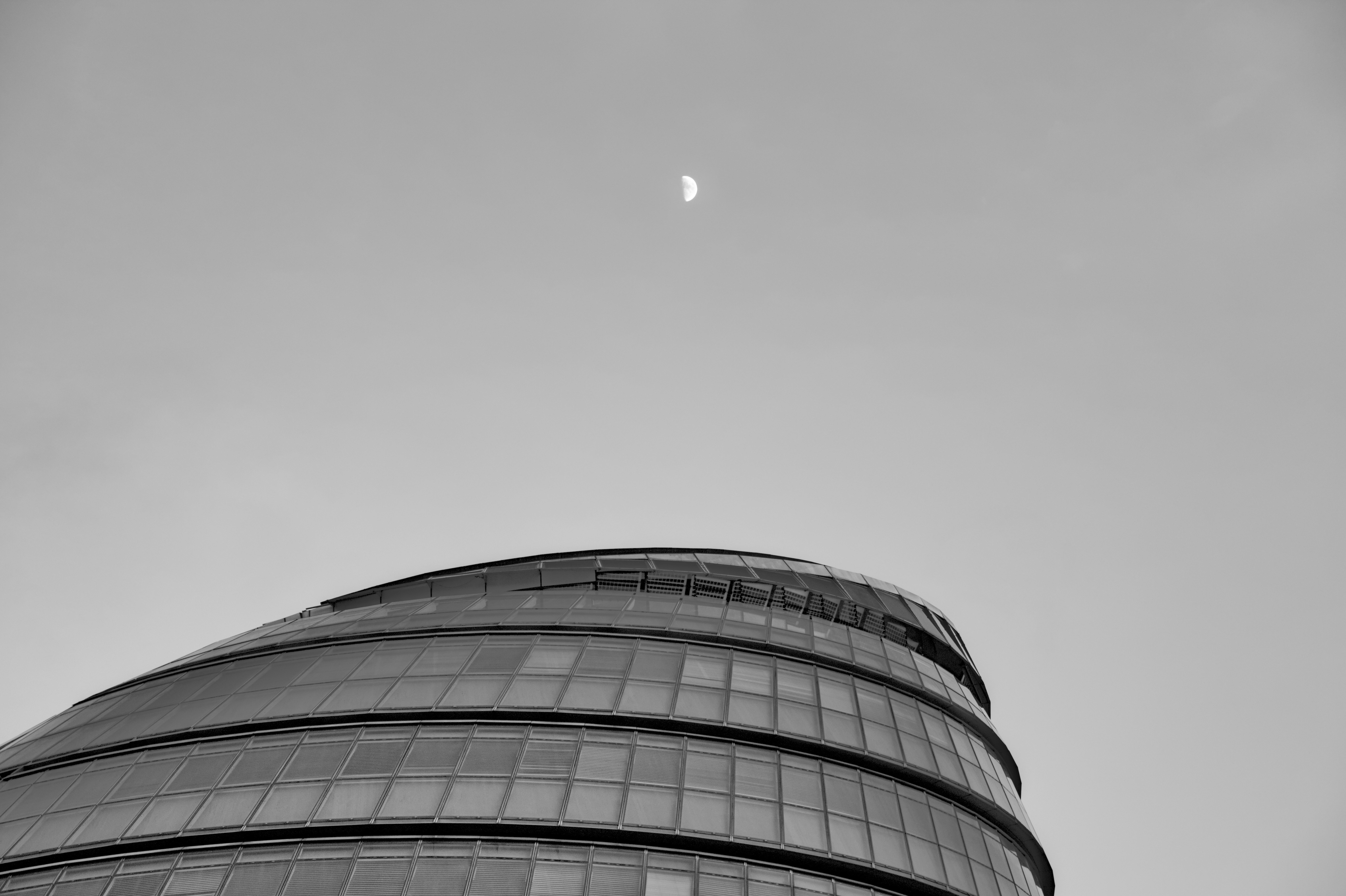 a black and white photo of a building with a half moon in the sky