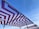 Geometric-patterned canopies with maroon and white zigzag designs are stretched over metal frames against a clear blue sky.
