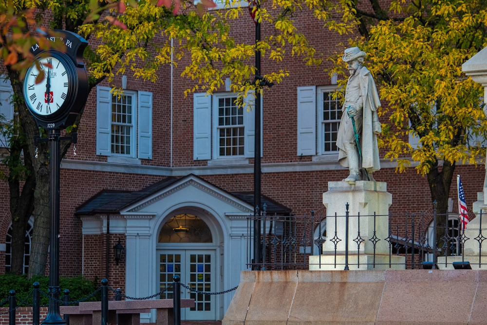 a clock and statue in front of a brick building