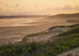 A tranquil beach in Timor-Leste at sunset, with gentle waves and colorful skies.