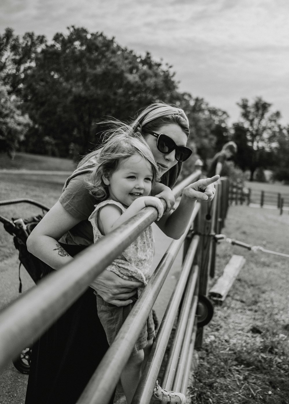 a woman and a little girl standing next to a fence