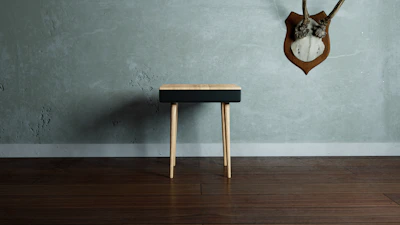 Minimalist Scandinavian-style wooden stool against an off-white background.
