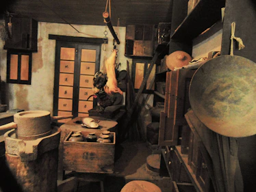 Artisan preparing ginguba-based dishes in a cozy kitchen with cultural decorations.