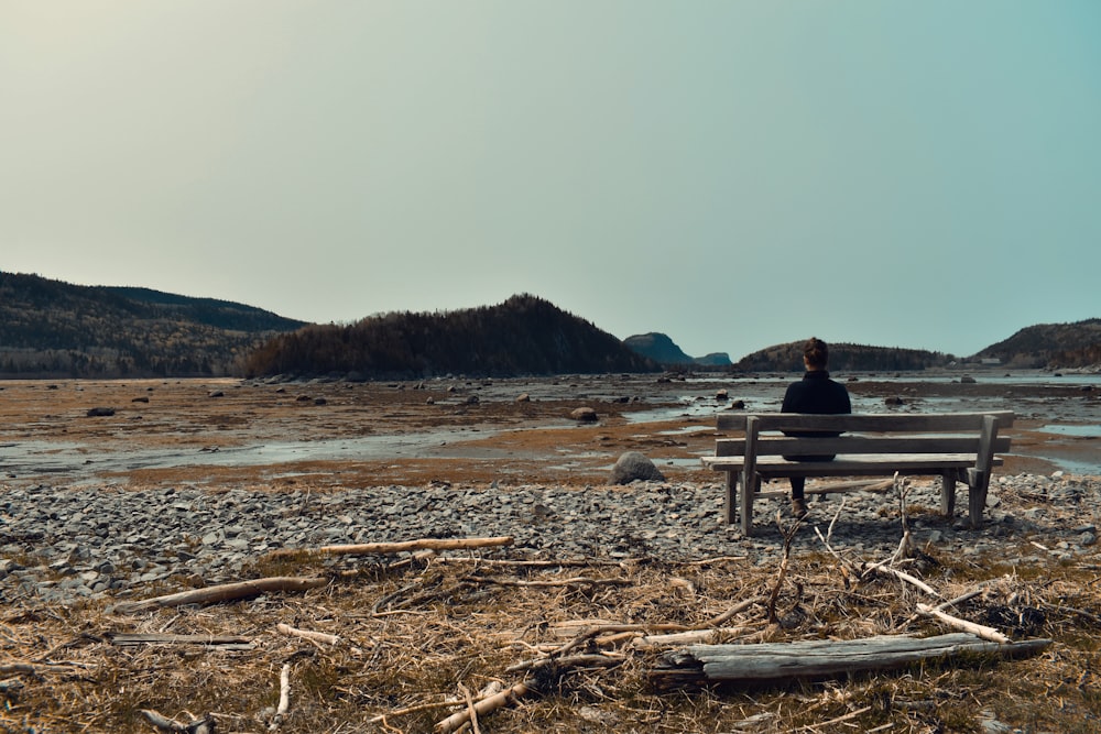 a person sitting on a bench near a body of water