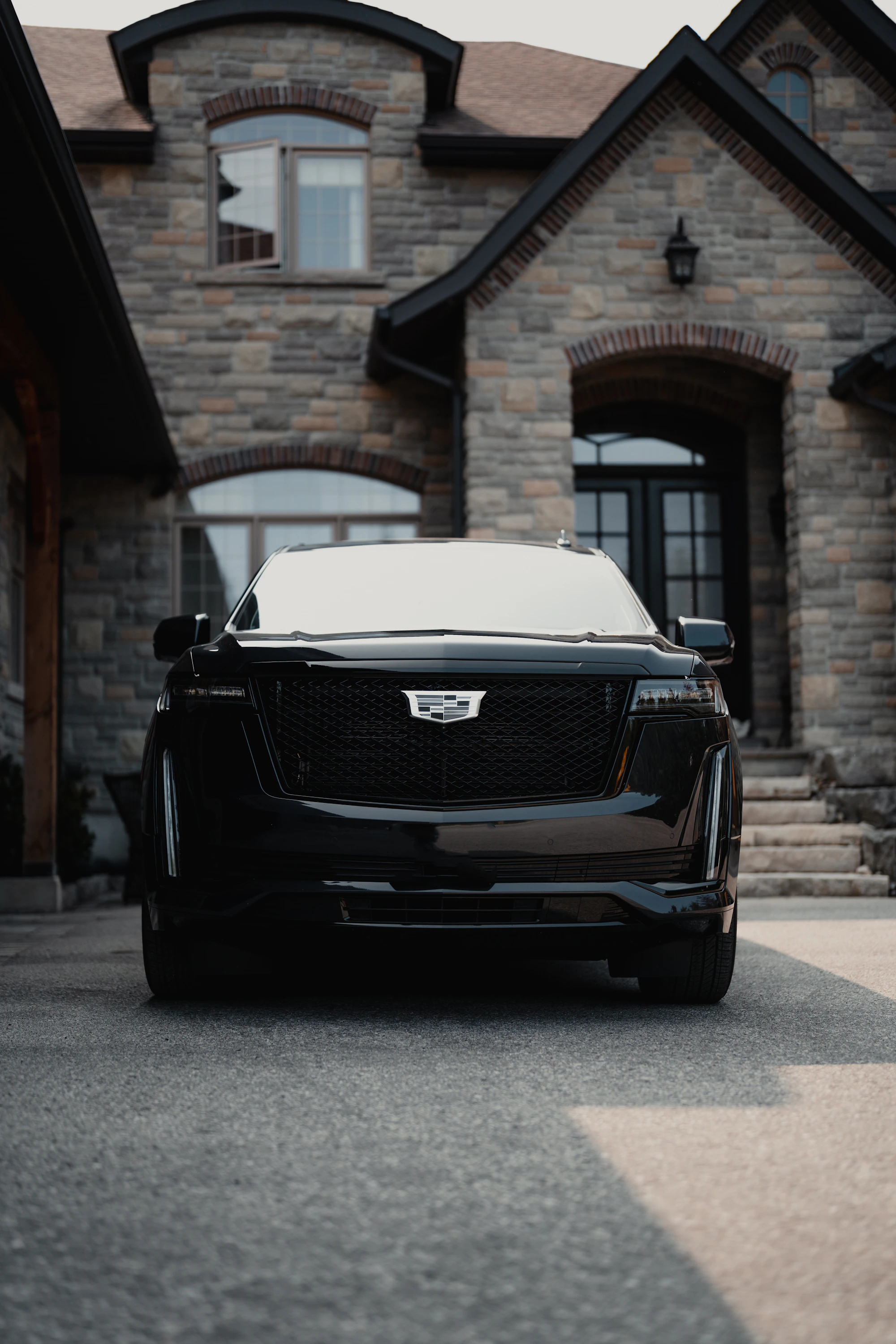Black luxury SUV being detailed in the driveway of an upscale home