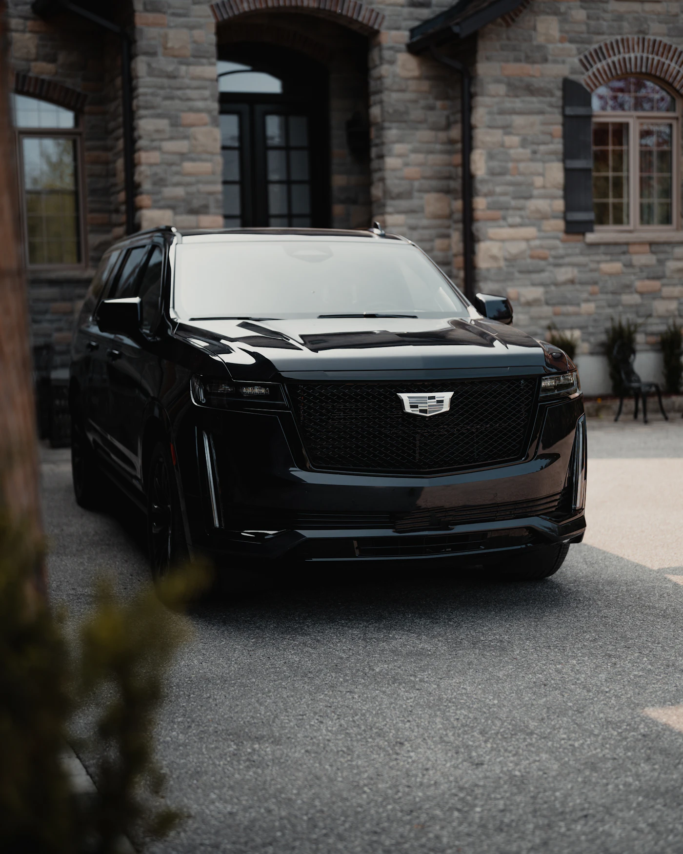 Black Cadillac Escalade waiting outside a stone building
