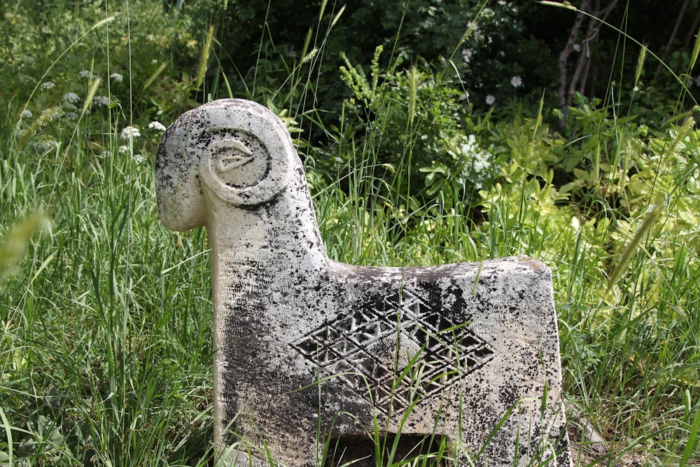 a statue of a goat in a field of grass