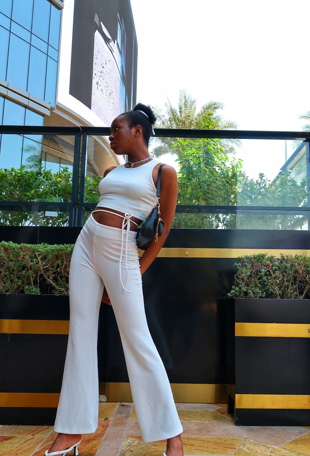 a woman in a white top and wide legged pants