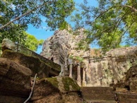 An ancient mysterious ruin partially covered by jungle greenery under sunlight.