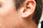 Close-up of a shiny ear piercing with a delicate silver hoop, highlighting the smooth skin around it.