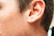 Close-up of a shiny ear piercing with a delicate silver hoop, highlighting the smooth skin around it.