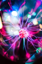 A vibrant display of energy with multicolored electrical arcs radiating from a central glowing orb. The arcs are primarily pink and purple against a dark background, suggesting dynamic movement and a high-tech atmosphere.