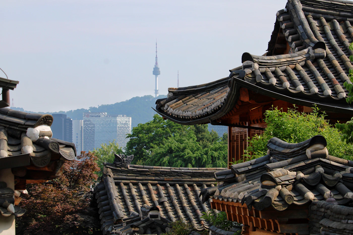 Traditional hanok rooftops below a Seoul mountain
