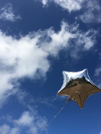 Shiny number-shaped balloons floating against a clear sky.