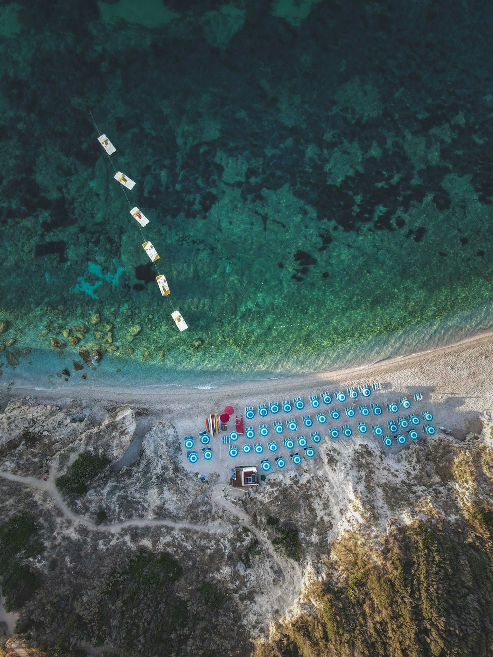 an aerial view of a beach with boats in the water