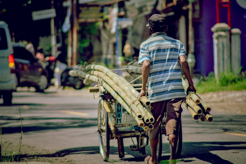 a man pushing a cart of bamboo down a street