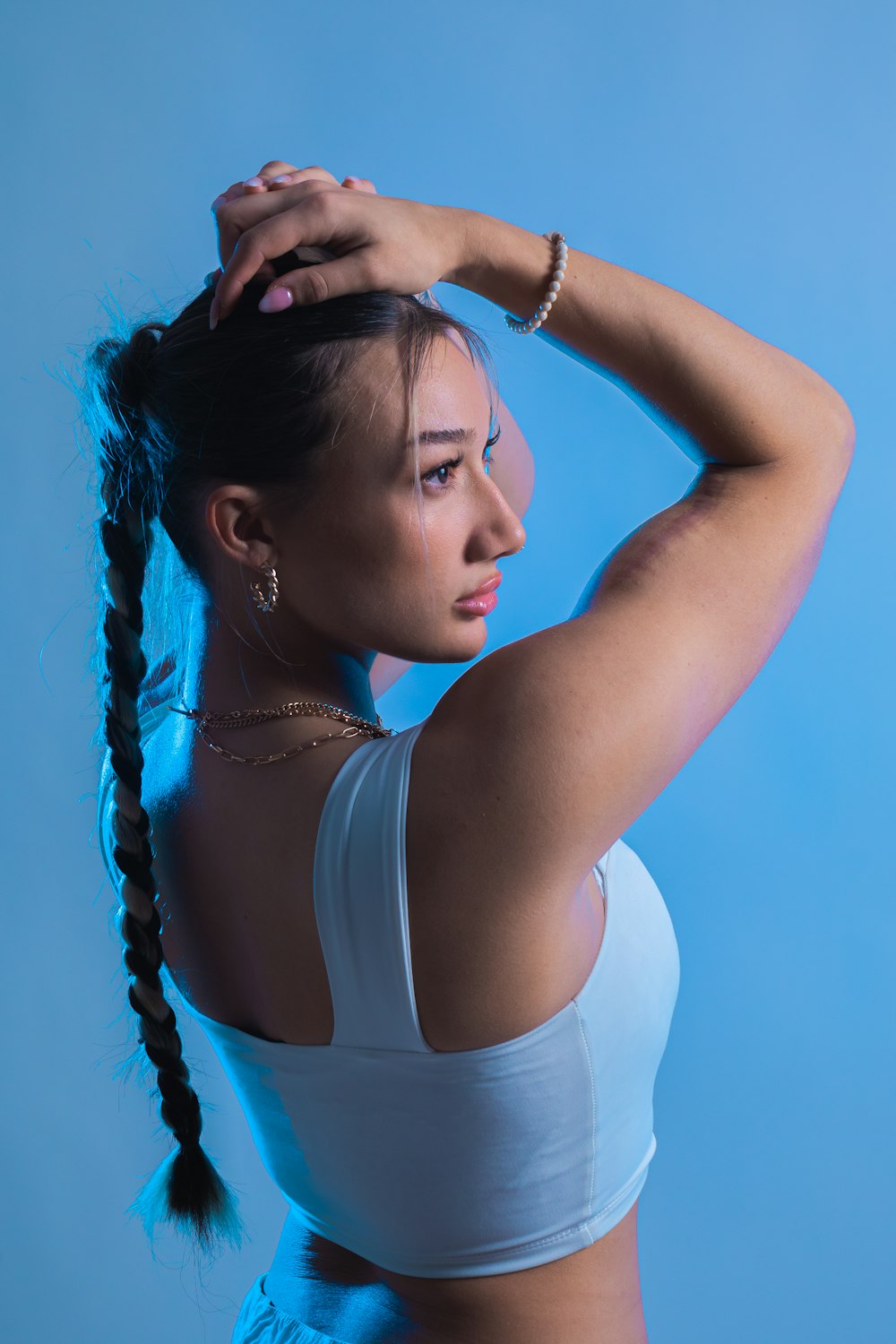 a woman in a white top is holding her hair