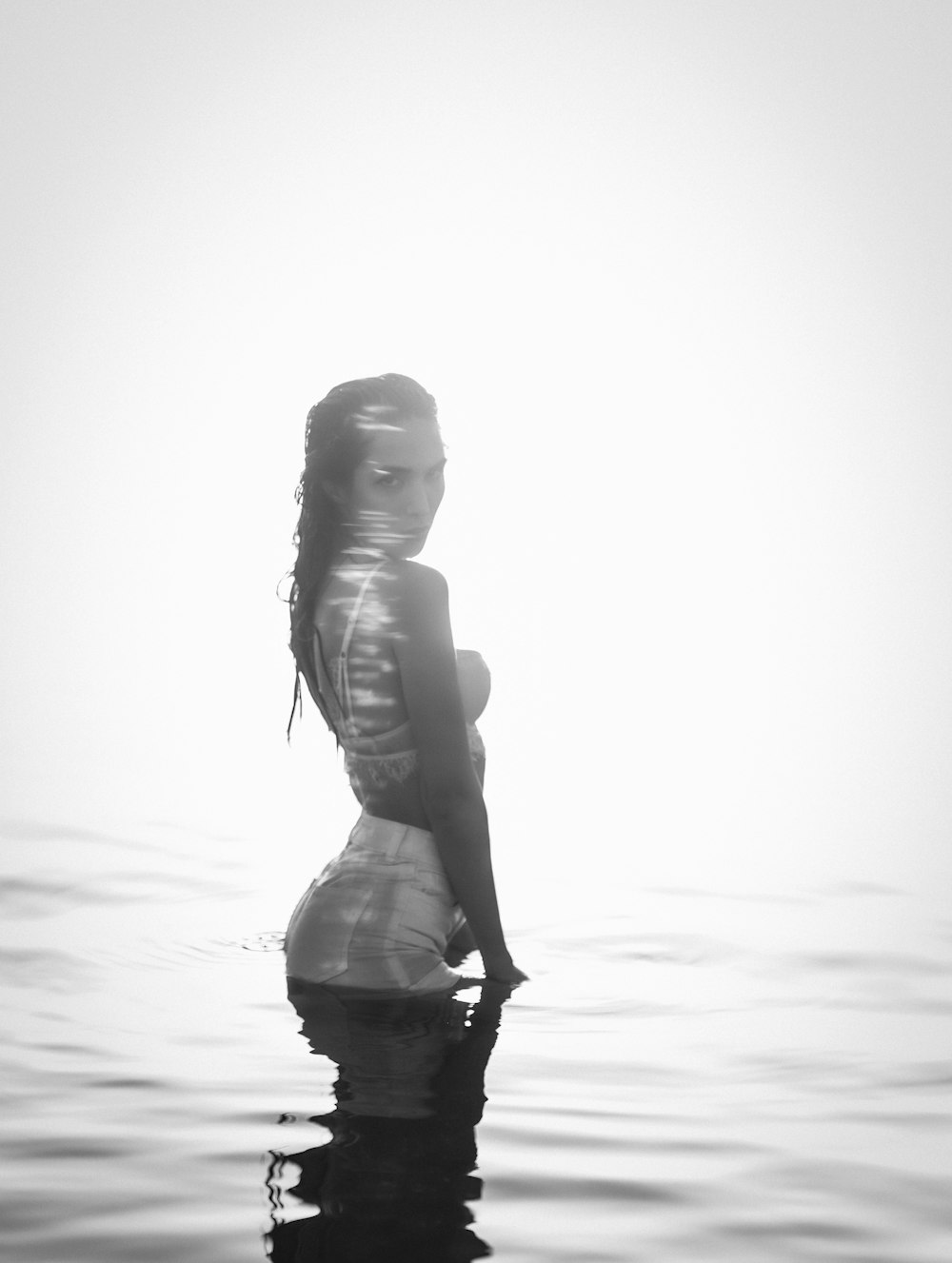a woman standing in the water with her back to the camera