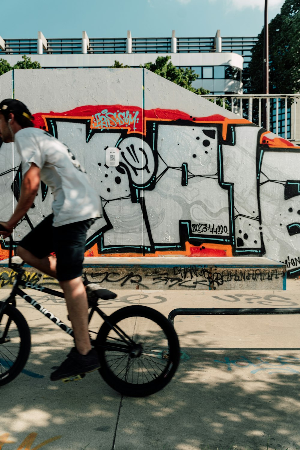 a man riding a bike in front of a graffiti covered wall