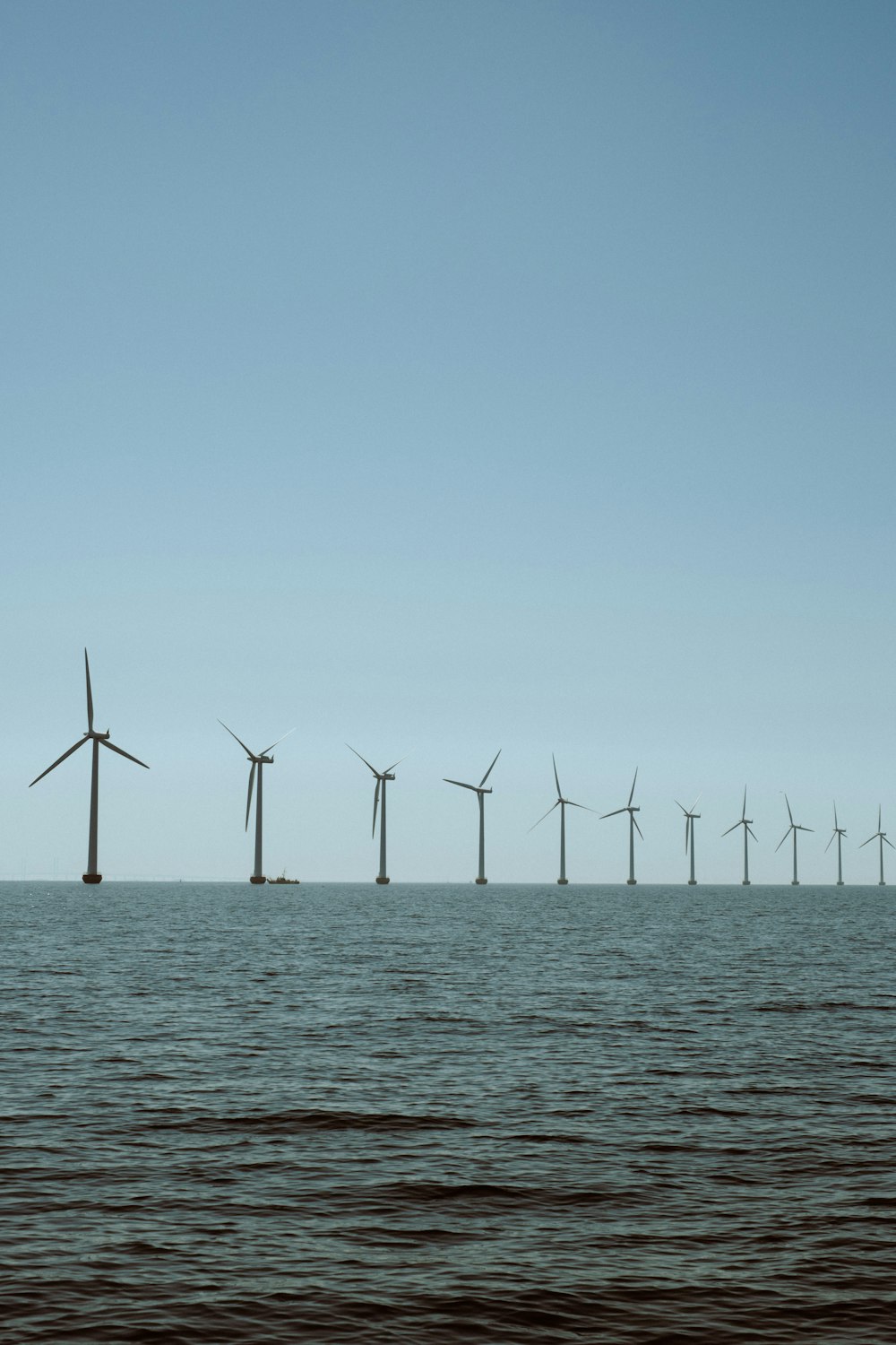 a row of wind turbines in the ocean