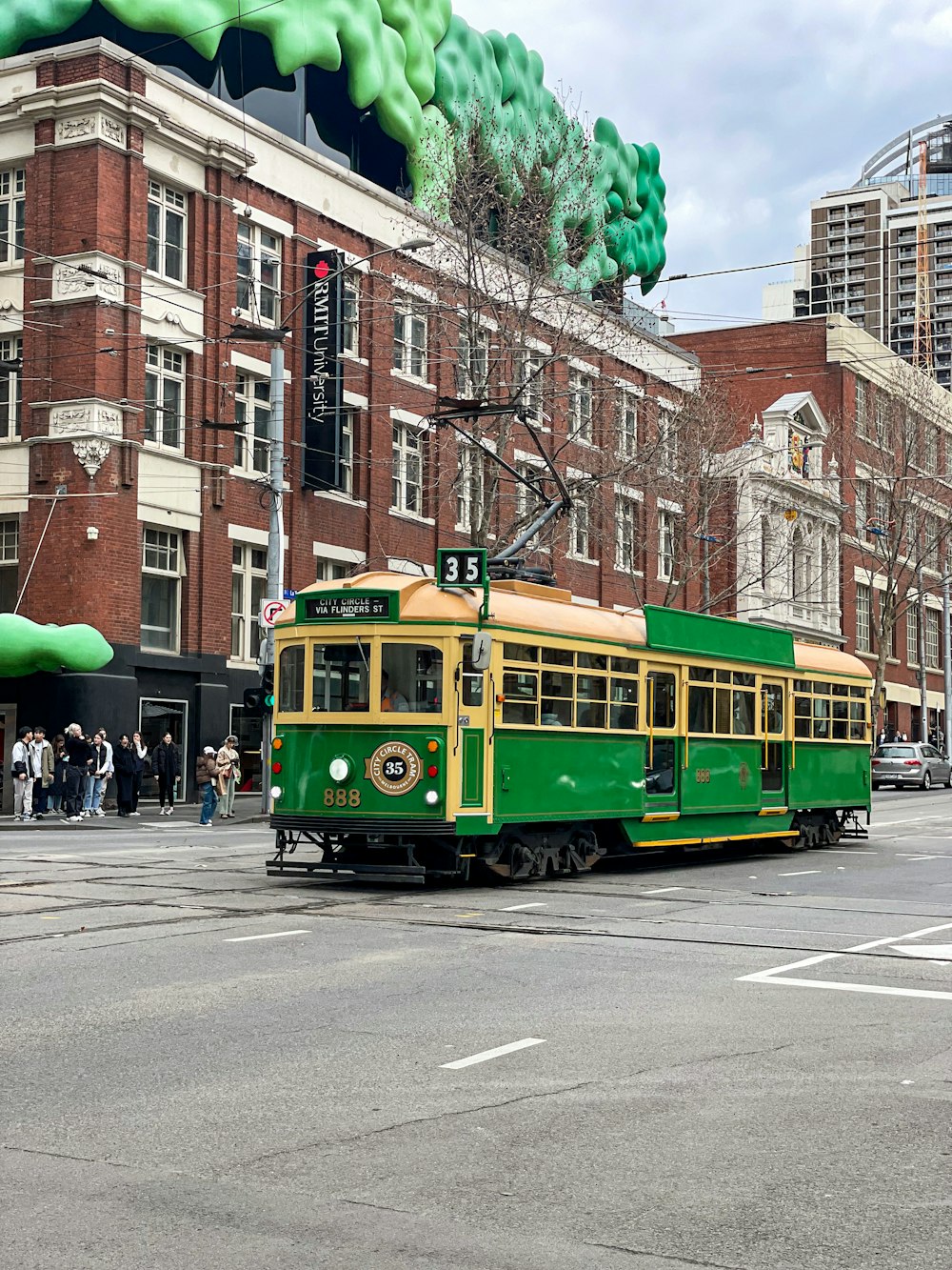 a green and yellow trolley on a city street