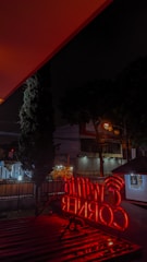 A bright neon box sign glowing at night outside a busy Surabaya shop.