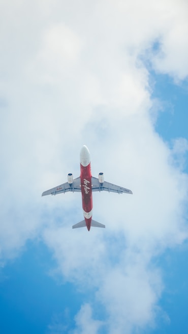 A vibrant red and white RC plane soaring against a clear blue sky