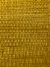 A close-up view of a textured fabric surface with a tight and even weave. The fabric appears to be made of thick threads, tightly interwoven in a grid pattern.