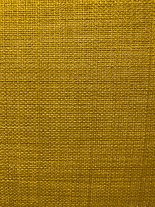 A close-up view of a textured fabric surface with a tight and even weave. The fabric appears to be made of thick threads, tightly interwoven in a grid pattern.
