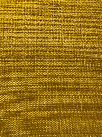 A close-up view of a textured fabric surface with a tight and even weave. The fabric appears to be made of thick threads, tightly interwoven in a grid pattern.