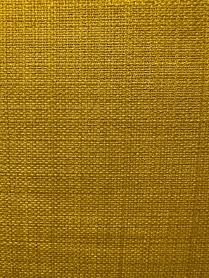A close-up view of a textured fabric surface with a tight and even weave. The fabric appears to be made of thick threads, tightly interwoven in a grid pattern.