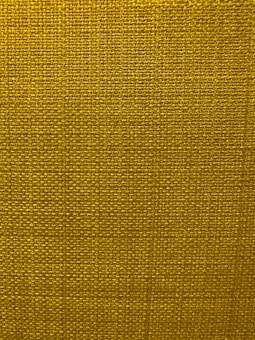 A close-up view of a textured fabric surface with a tight and even weave. The fabric appears to be made of thick threads, tightly interwoven in a grid pattern.