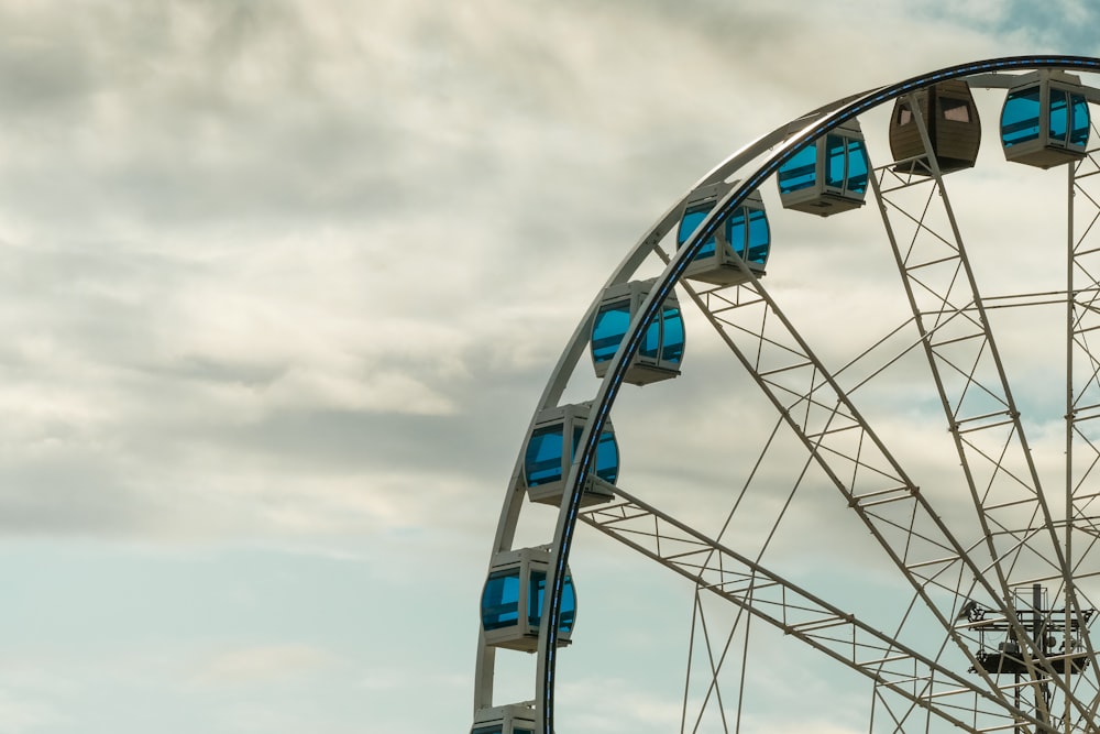 a ferris wheel with blue seats on a cloudy day
