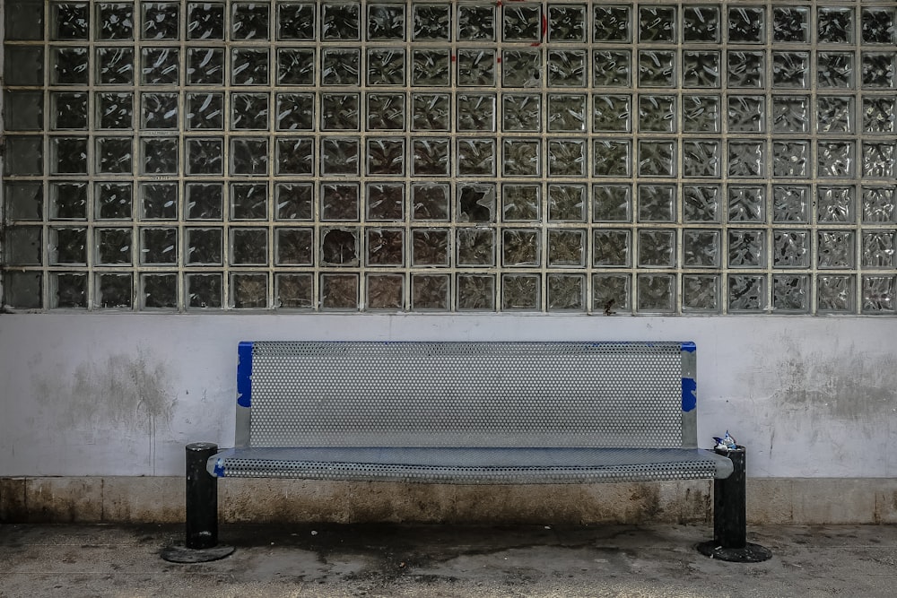 a metal bench sitting in front of a wall