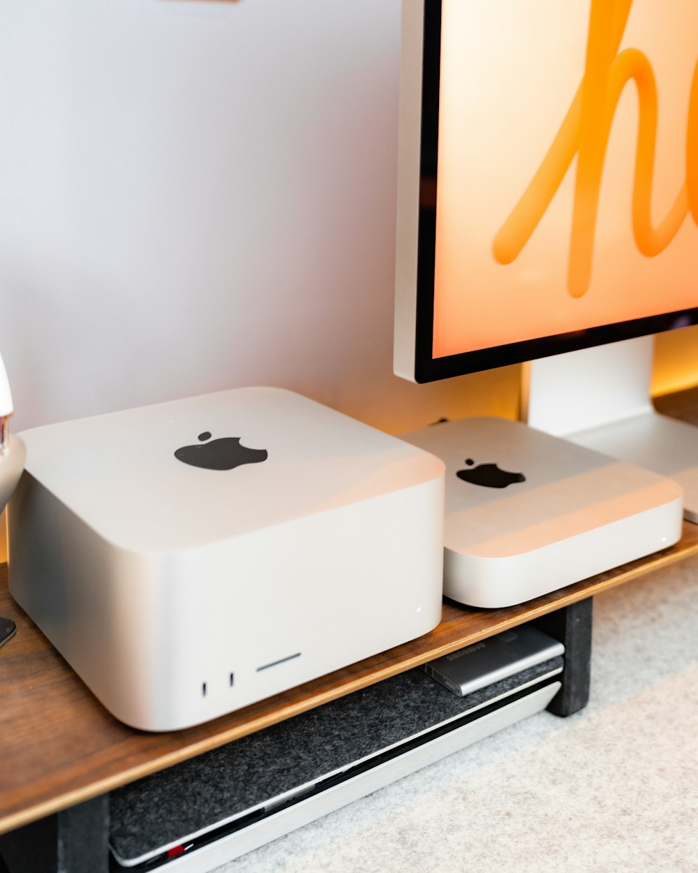 a couple of apple computers sitting on top of a wooden desk