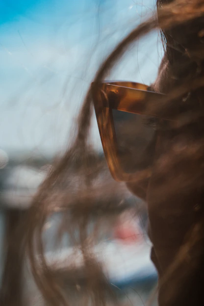 Close-up of a person wearing sleek, modern talking eye sunglasses with a soft sunlit background